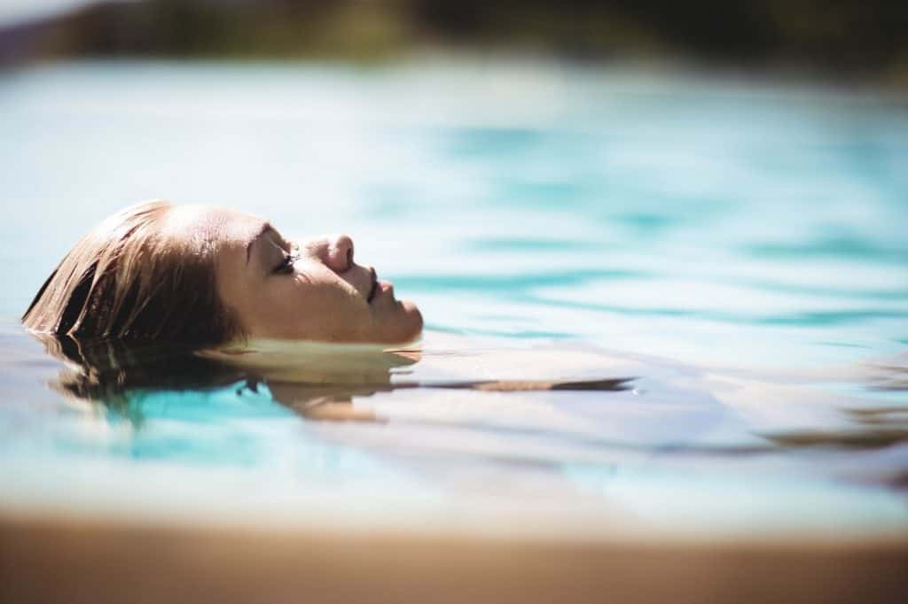 Peaceful blonde floating in the pool with eyes closed